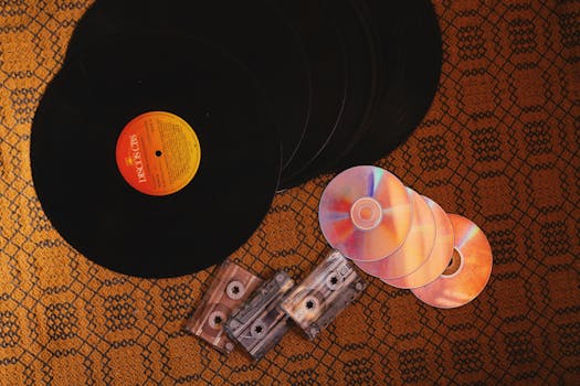 A nostalgic collection of retro music formats including vinyl records, CDs, and cassettes on a patterned surface.